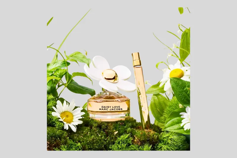 Perfume Marc Jacobs Daisy 100ml com flores ao fundo destacando sua proposta floral fresca.
