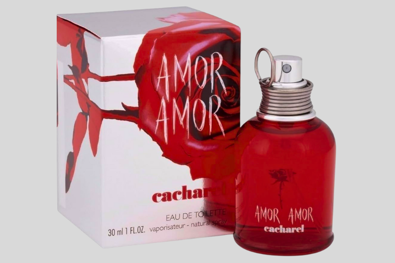 Perfume Amor Amor da Cacharel em destaque com fundo vermelho vibrante e detalhes metálicos elegantes.