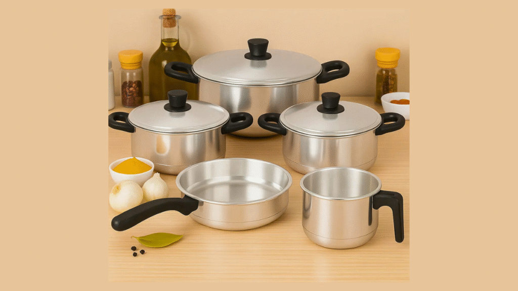 Conjunto de panelas de cozinha em inox organizadas sobre a bancada ao lado de alimentos e utensílios.