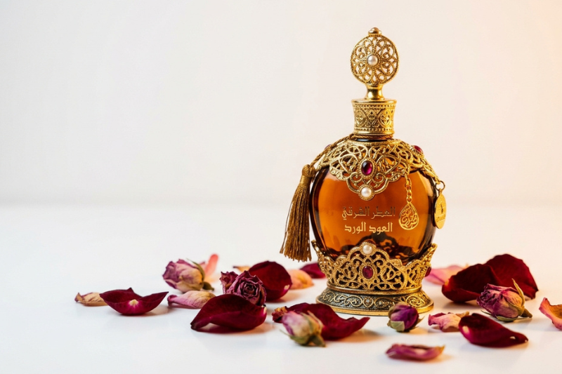Top 5 perfumes 2026 — frasco de perfume oriental árabe com pétalas de rosa