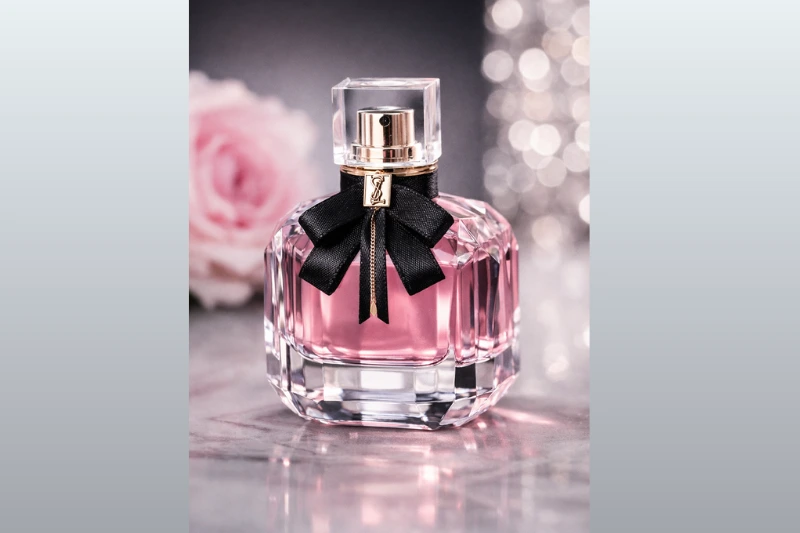 Perfume YSL Mon Paris Feminino 50ml da Yves Saint Laurent, frasco de vidro com líquido rosa e laço preto, símbolo de elegância e romance.