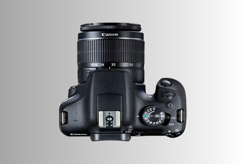 Vista superior da câmera DSLR Canon com lente 18-55mm destacando controles e seletor de modos.