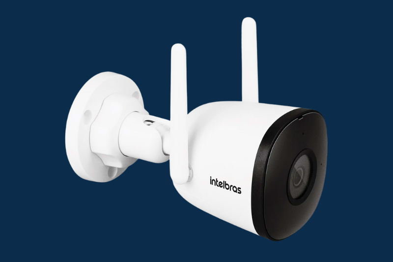 Câmera de segurança Intelbras branca fixada na parede sobre fundo azul escuro