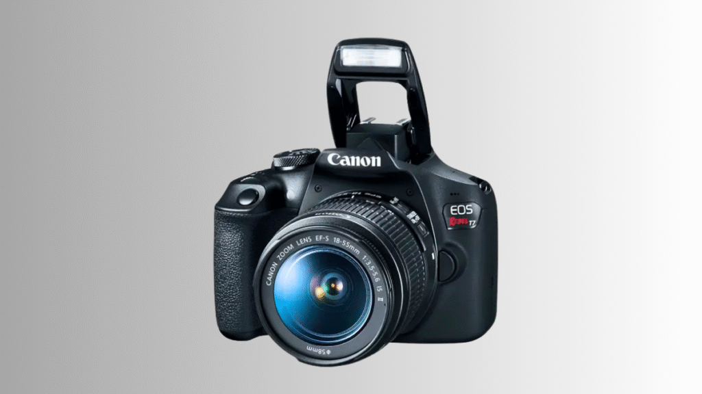 Câmera DSLR Canon EOS Rebel T7 com lente 18-55mm exibida de frente com flash pop-up acionado sobre fundo cinza.