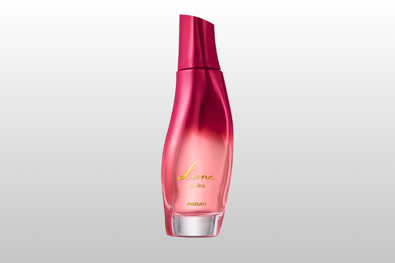 Imagem de um frasco de perfume rosa com design alongado e tampa no mesmo tom, sobre fundo cinza claro.