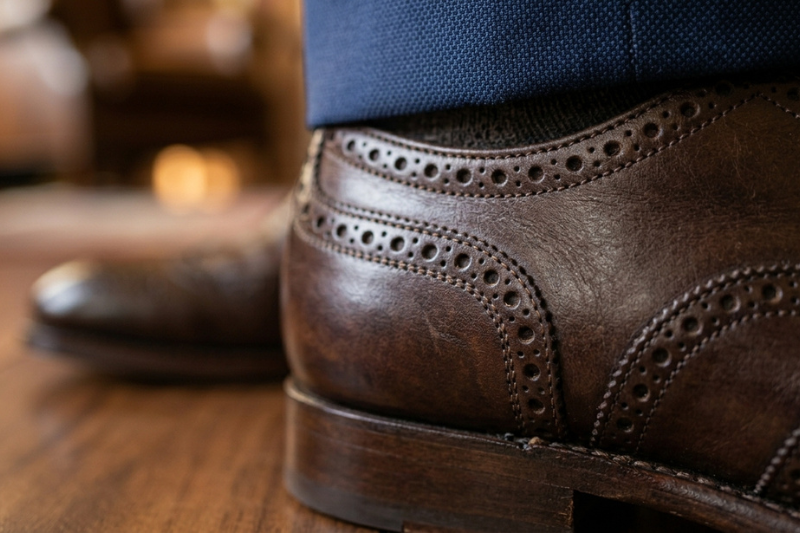 Sapato social masculino em couro marrom com foco nos detalhes e fundo desfocado em bokeh