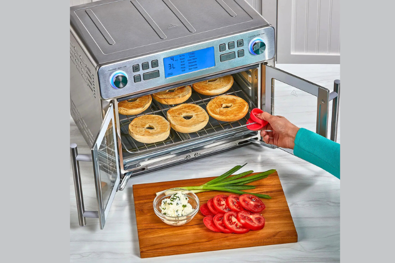 Air Fryer Forno 25L Emeril Lagasse em uso, com porta aberta e preparo de pães no interior do forno